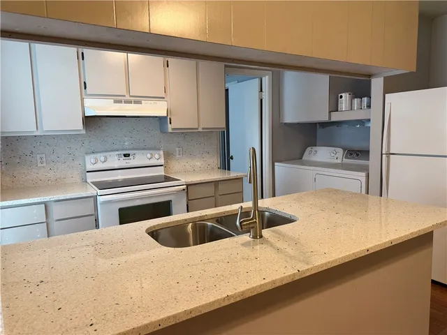 a kitchen with granite countertop a sink a stove and refrigerator