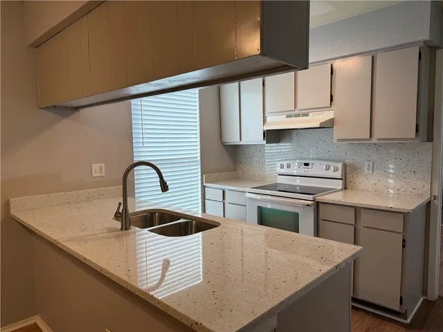 a kitchen with stainless steel appliances granite countertop a sink dishwasher and stove with wooden cabinets