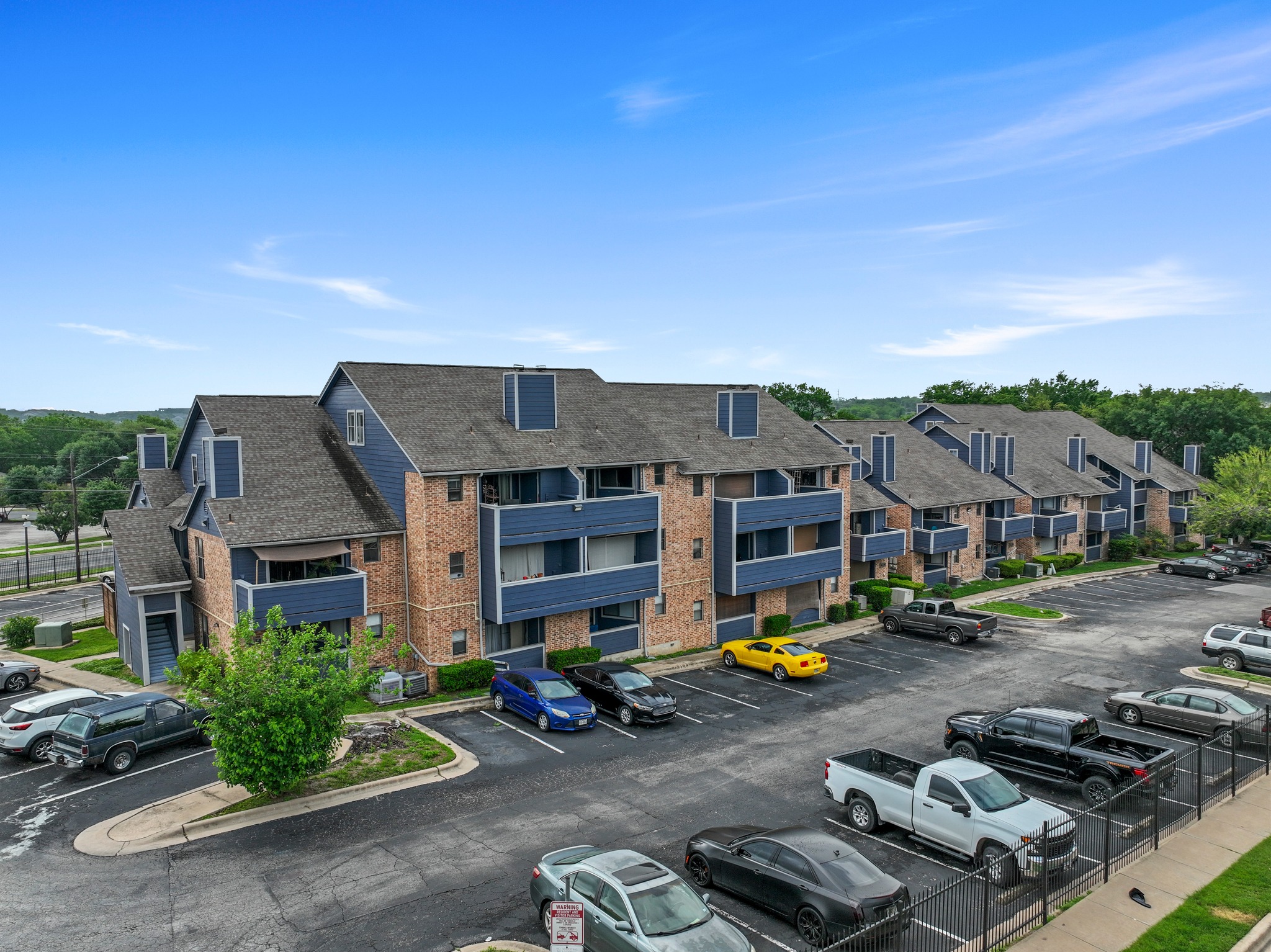 2500 Burleson Road, Unit 713 Austin, TX 78741 - Photo 14 of 15 A striking apartment complex with blue siding and brick accents offers ample parking and lush landscaping.