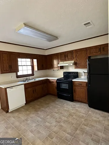 a area with granite countertop a refrigerator and a stove top oven