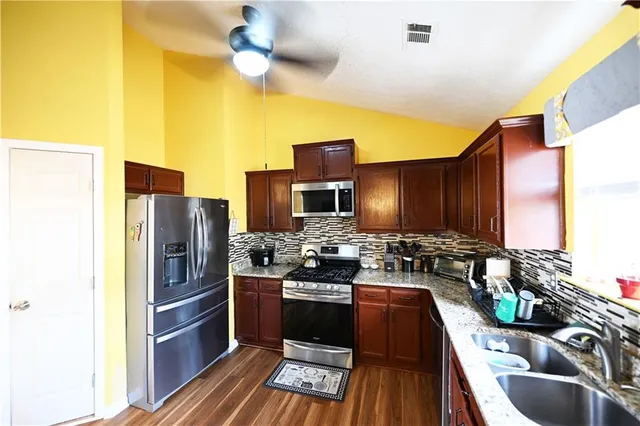 a kitchen with stainless steel appliances granite countertop a stove refrigerator and cabinets