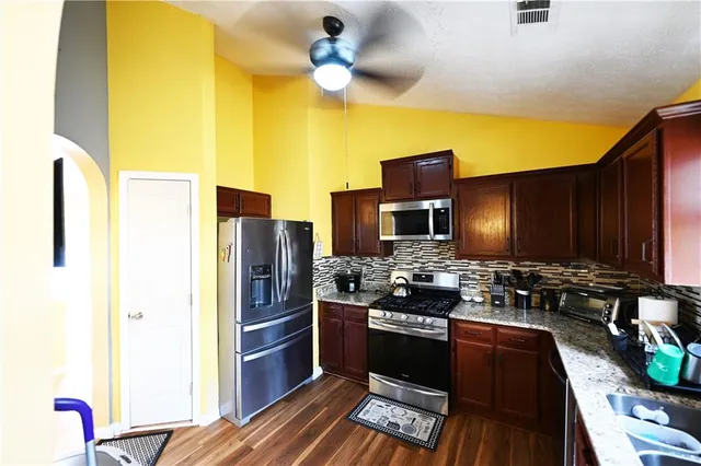 a kitchen with stainless steel appliances granite countertop a stove refrigerator and microwave