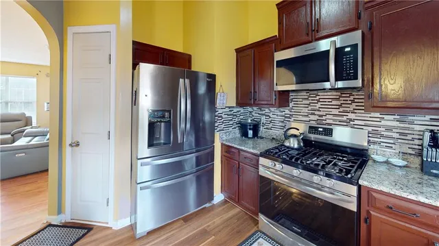 a kitchen with stainless steel appliances granite countertop a stove microwave refrigerator and sink