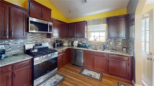 a kitchen with granite countertop wooden cabinets stainless steel appliances and a window