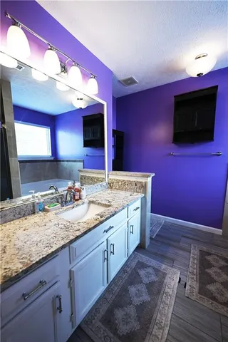 a kitchen with a sink dishwasher a microwave oven with granite countertops and a flat screen tv