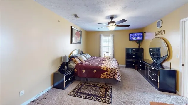 a bedroom with a bed dresser and a flat screen tv