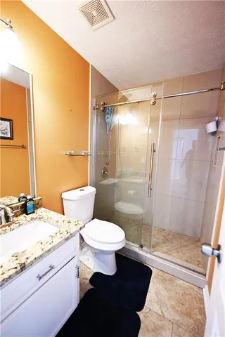 a bathroom with a granite countertop sink toilet and shower