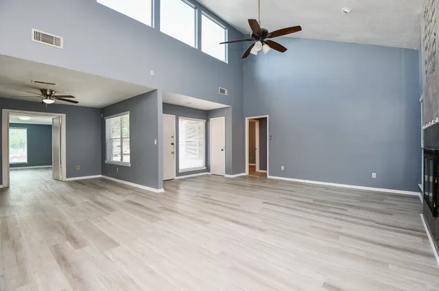 a view of an empty room with window and wooden floor