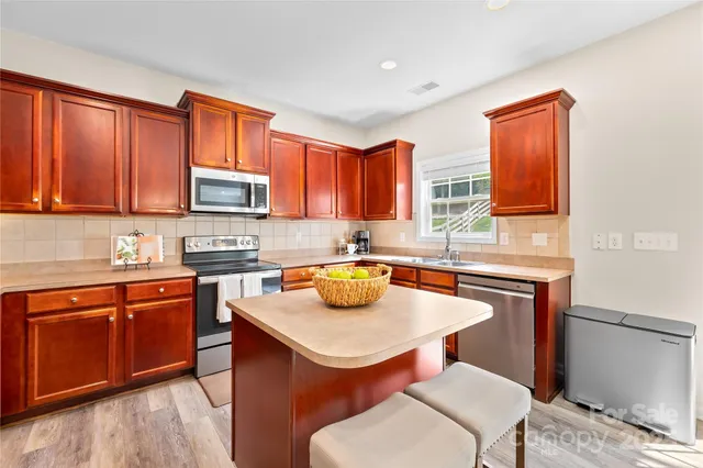 a kitchen with a stove a sink dishwasher a dining table and chairs with wooden floor