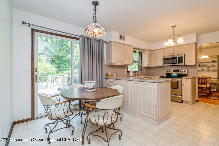 1711 Glendola Road Wall, NJ 07719 - Photo 9 of 25 a kitchen with stainless steel appliances granite countertop a stove a refrigerator a microwave oven a dining table and chairs with wooden floor
