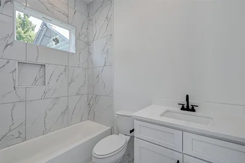 a bathroom with a bathtub shower sink vanity and toilet