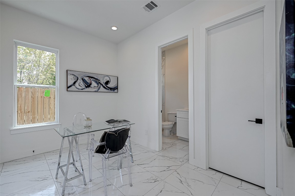 6032 Beall Street Houston, TX 77091 - Photo 14 of 26 This versatile space on the first level is perfect as a guest bedroom or stylish home office. With marble-look tile flooring, natural light, and a private en-suite bath, it offers both function and flair for work or rest.