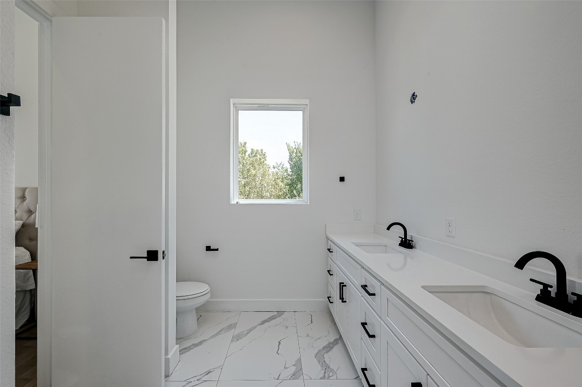 6032 Beall Street Houston, TX 77091 - Photo 21 of 26 Bathed in natural light, this spacious en-suite bathroom features a stunning double vanity, private toilet area, and serene treetop views.