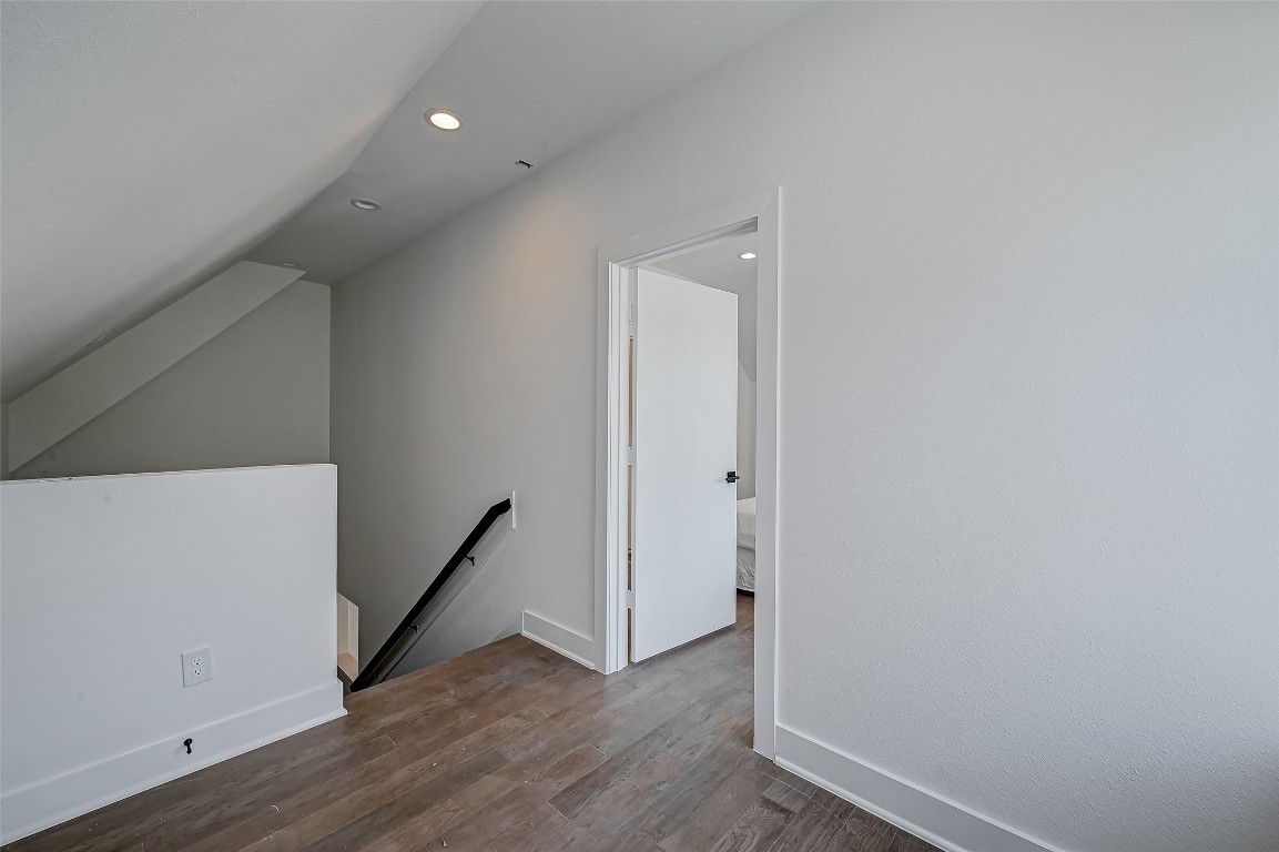 6032 Beall Street Houston, TX 77091 - Photo 22 of 26 This upper landing offers seamless access to the home’s private quarters while showcasing wide wood floors and modern finishes. The angled ceiling and black metal stair railing add architectural interest and a contemporary edge.