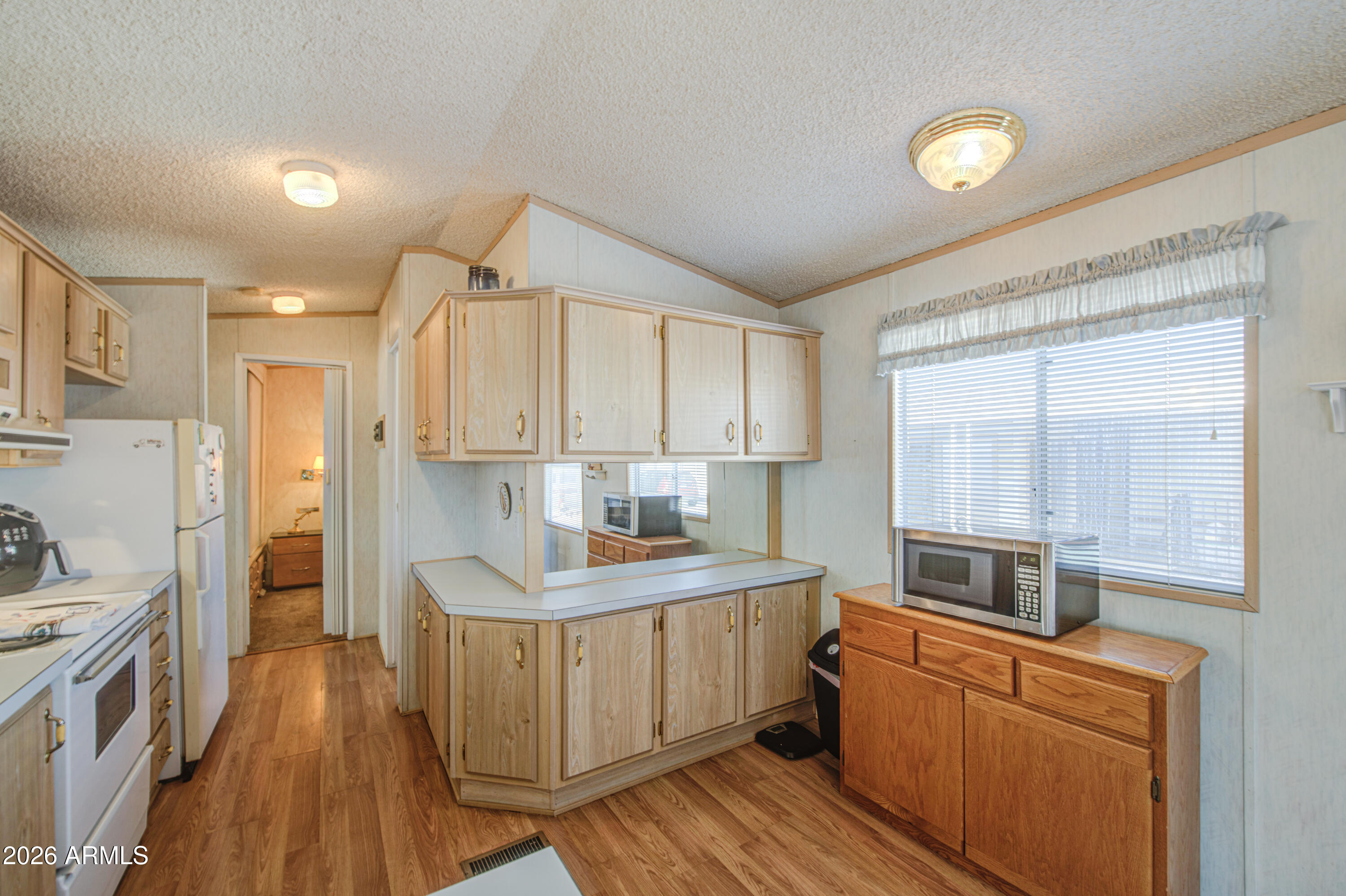7750 East Broadway Road, Unit 273 Mesa, AZ 85208 - Photo 6 of 36 a kitchen with granite countertop a stove top oven a sink dishwasher and a refrigerator with wooden floor