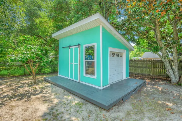 a view of a small house with a big yard plants and large tree
