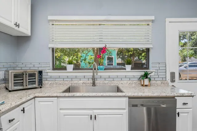 a kitchen with stainless steel appliances granite countertop a sink and a wooden floor