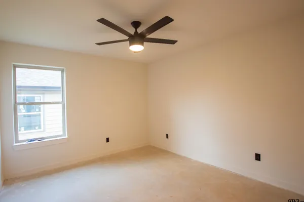 an empty room with windows and fan