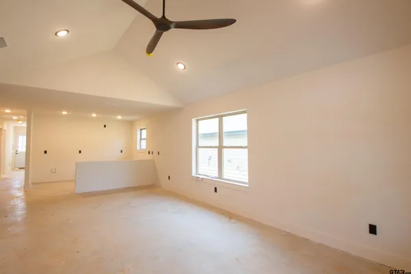 an empty room with windows and ceiling fan
