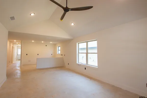 an empty room with windows and ceiling fan