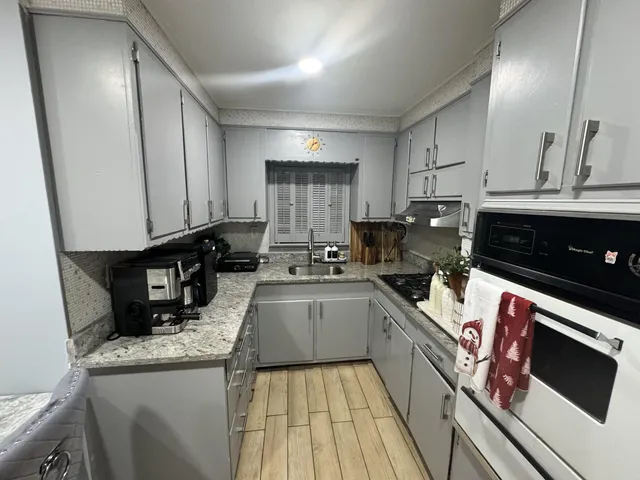a kitchen with granite countertop a sink a stove and cabinets