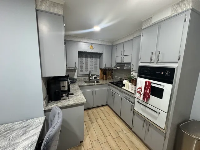 a kitchen with a sink dishwasher stove and white cabinets