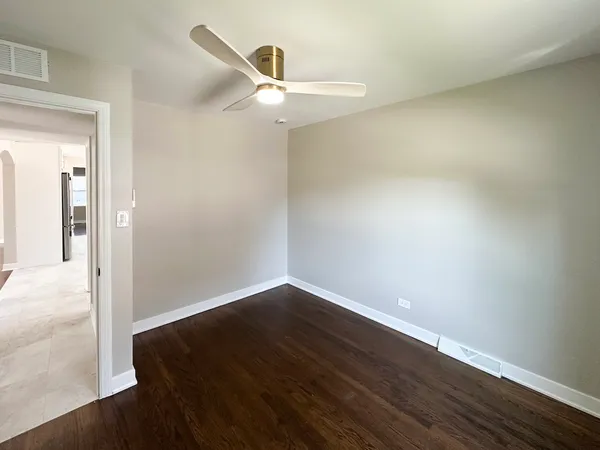 an empty room with wooden floor fan and windows