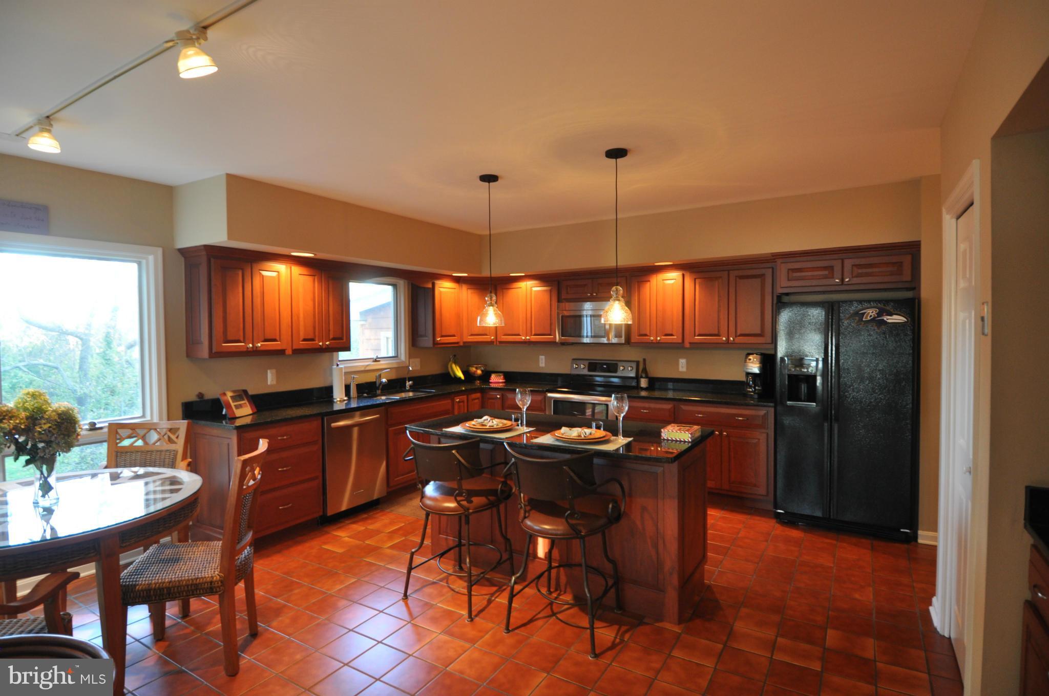 1890 Hidden Point Road Annapolis, MD 21409 - Photo 8 of 30 a kitchen with stainless steel appliances granite countertop a stove a refrigerator a sink a dining table and chairs with wooden floor