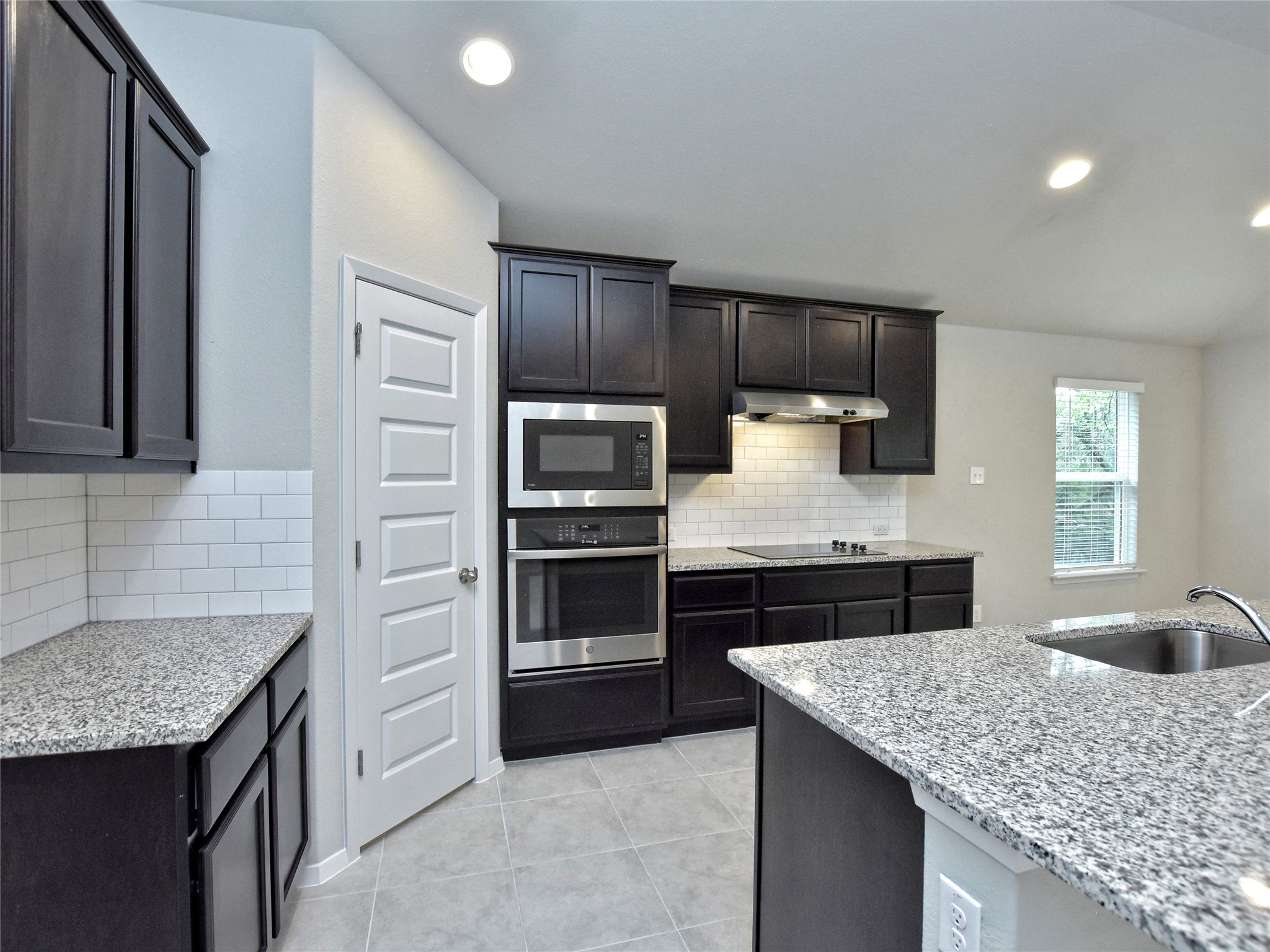 20701 Boggy Ford Road Lago Vista, TX 78645 - Photo 11 of 40 Kitchen featuring light stone countertops, stainless steel appliances, backsplash, light tile patterned floors, and vaulted ceiling