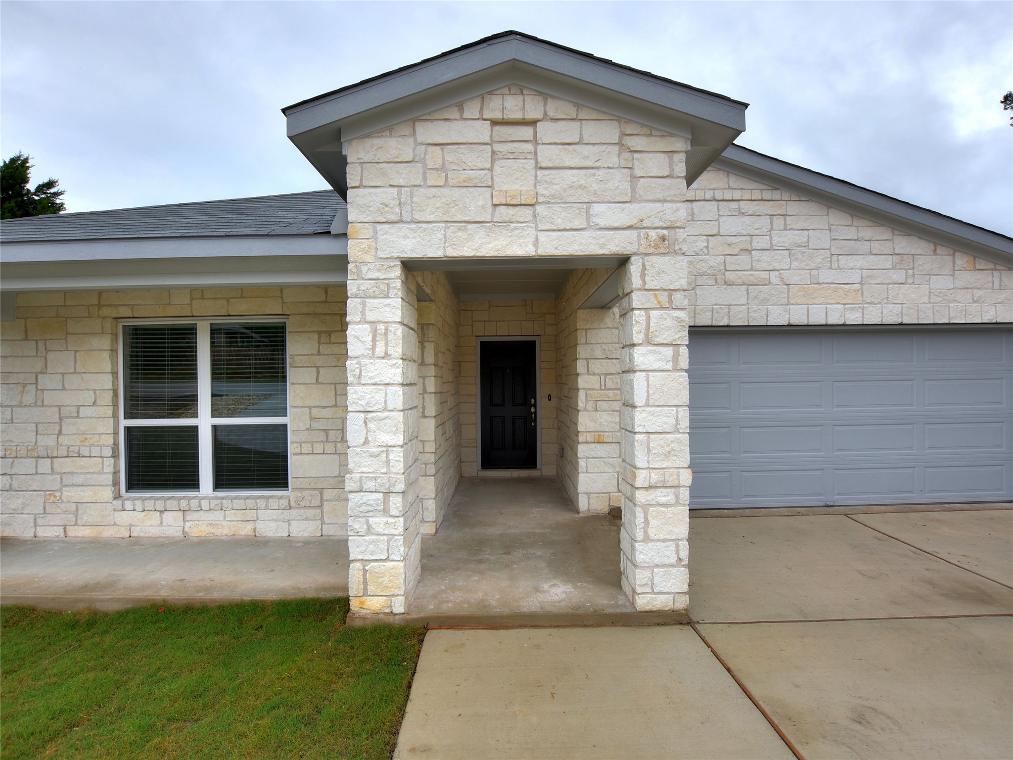 20701 Boggy Ford Road Lago Vista, TX 78645 - Photo 3 of 40 Entrance to property with an attached garage, stone siding, and concrete driveway