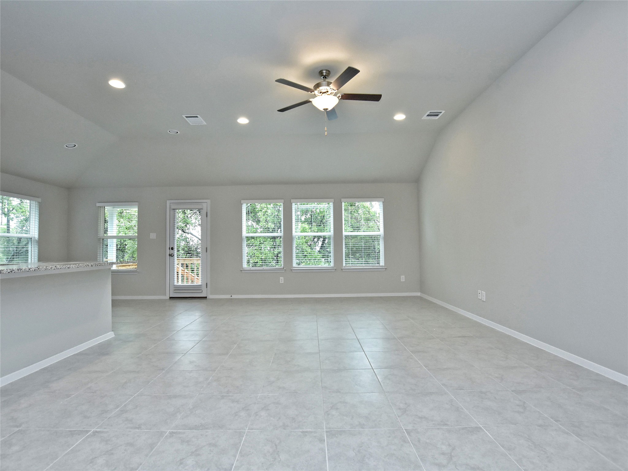 20701 Boggy Ford Road Lago Vista, TX 78645 - Photo 6 of 40 Unfurnished living room featuring lofted ceiling, ceiling fan, light tile patterned floors, and recessed lighting