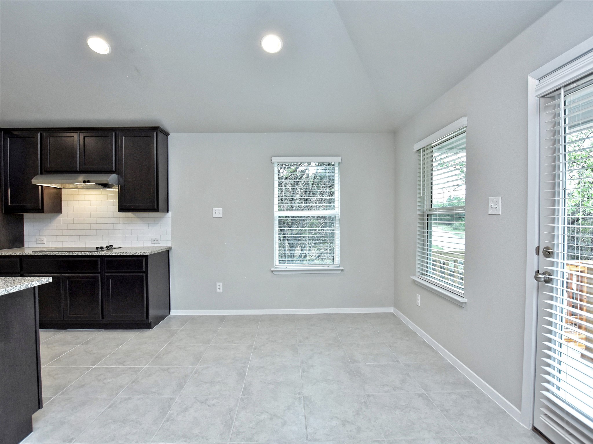 20701 Boggy Ford Road Lago Vista, TX 78645 - Photo 8 of 40 Kitchen featuring light stone countertops, decorative backsplash, dark wood finish cabinets, recessed lighting, and light tile patterned floors
