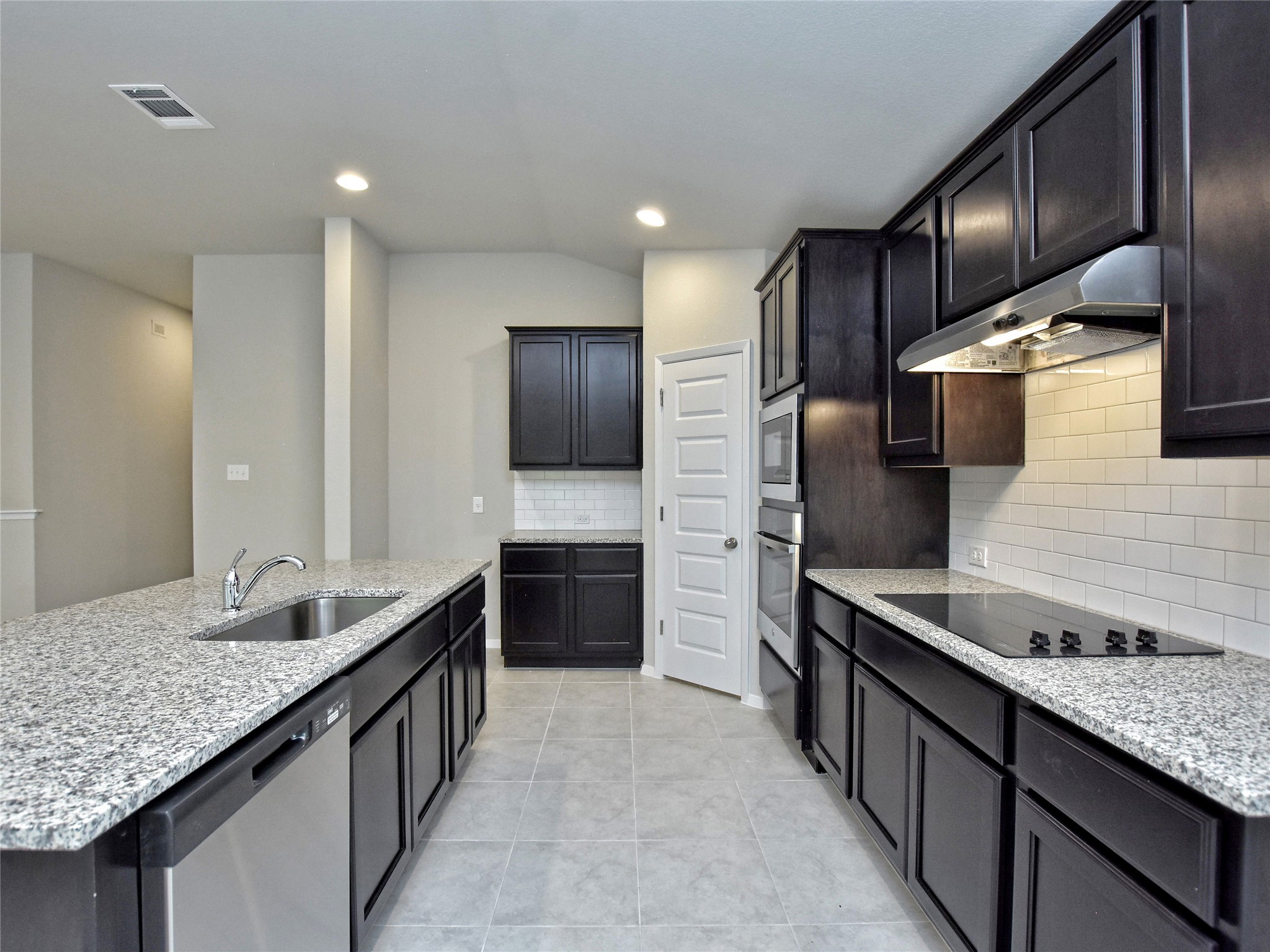 20701 Boggy Ford Road Lago Vista, TX 78645 - Photo 9 of 40 Kitchen with stainless steel appliances, light stone counters, a kitchen island with sink, backsplash, and recessed lighting