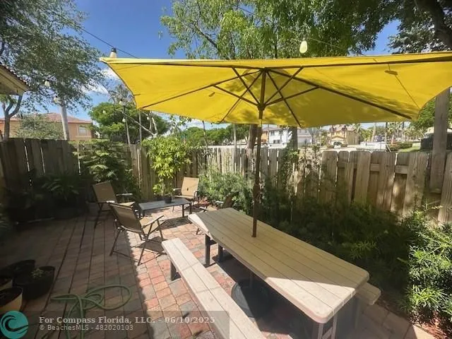 a view of patio with chairs and table under an umbrella