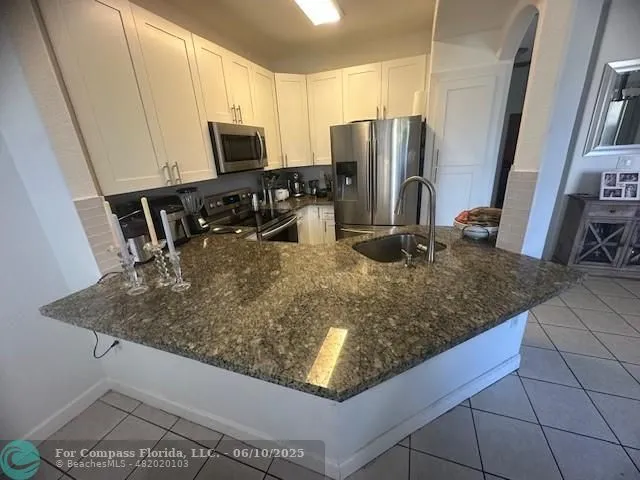 a kitchen with kitchen island granite countertop a sink a microwave a refrigerator and counter space