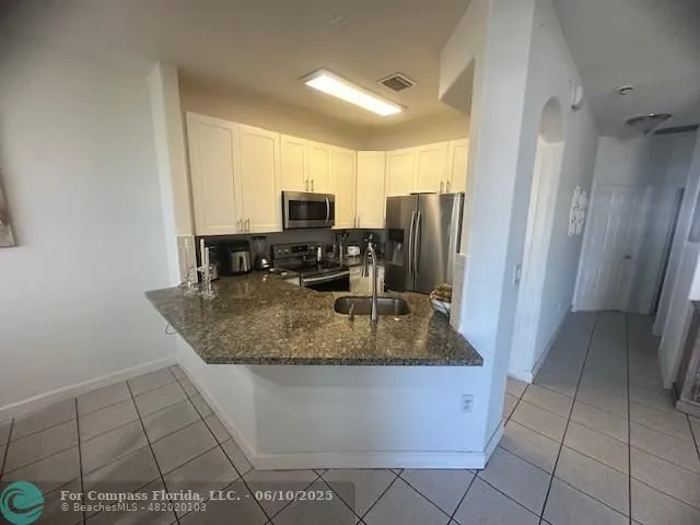 a kitchen with stainless steel appliances granite countertop a sink a stove and a refrigerator