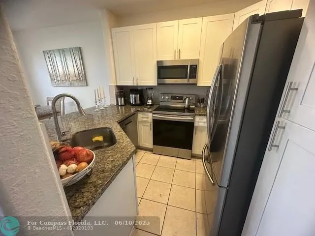 a kitchen with stainless steel appliances granite countertop a refrigerator sink and stove