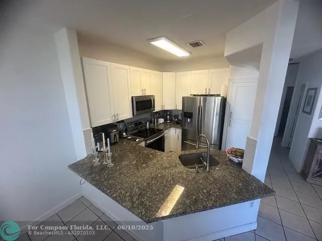 a kitchen with a sink a counter top space appliances and cabinets