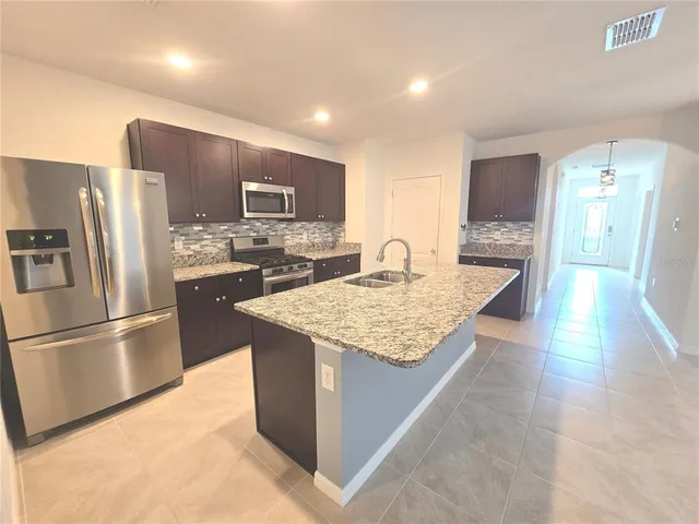 a kitchen with stainless steel appliances granite countertop a refrigerator stove top oven and a sink