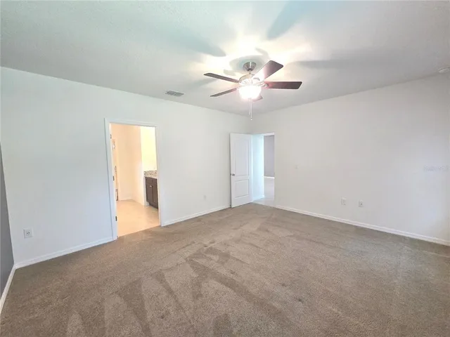 a view of an empty room with a chandelier fan