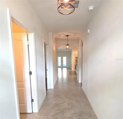 a view of a hallway with wooden floor and chandelier