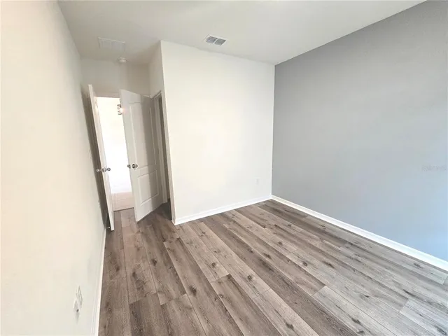 an empty room with wooden floor and a bathroom