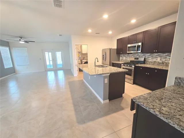 a large kitchen with kitchen island a sink a counter top space appliances and cabinets