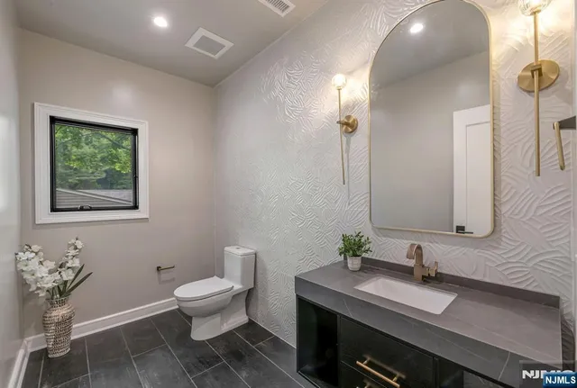 a bathroom with a granite countertop sink and a toilet