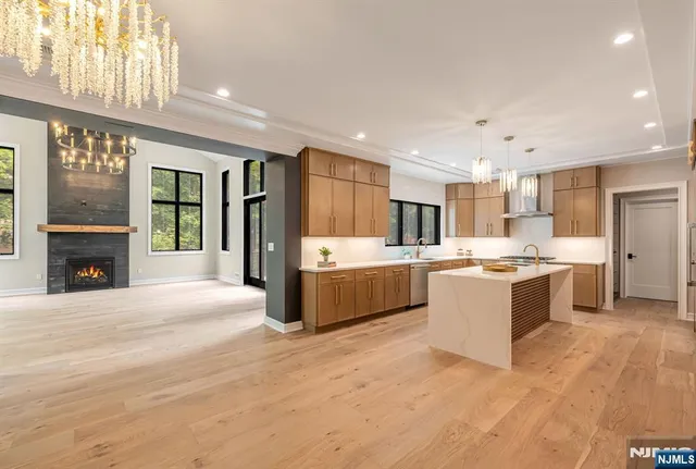 a large kitchen with a large counter top a sink stainless steel appliances and cabinets