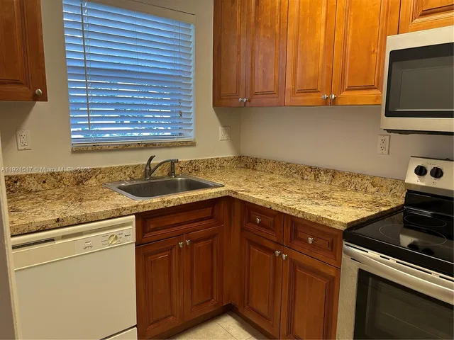 a kitchen with granite countertop a sink stove and cabinets