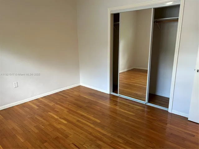 a view of an empty room with wooden floor and closet
