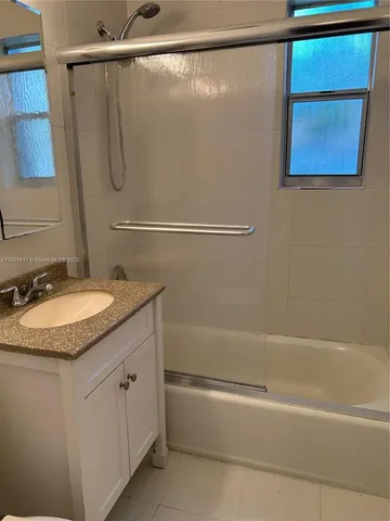 a bathroom with a granite countertop sink mirror vanity and a bathtub