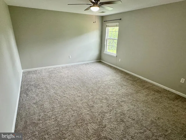 an empty room with a chandelier fan and windows