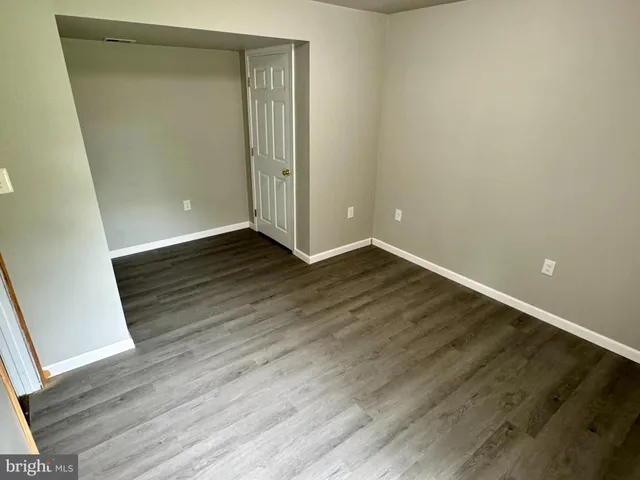 an empty room with wooden floor and entrance